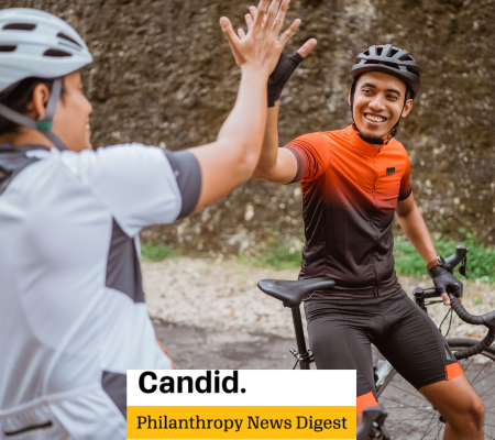 two cyclists giving each other a high five on their bikes